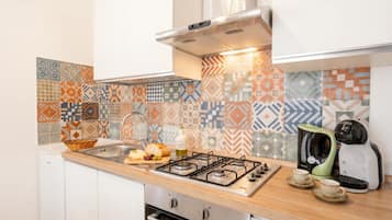 Una cucina con piano cottura a gas, macchina del caffè e lavandino.