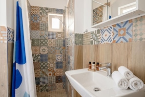 A bathroom with a shower, a sink, and a mirror.
