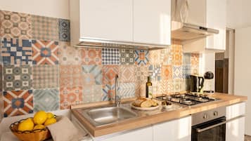 Una cucina con piastrelle decorate, un lavello, un fornello e un cesto di limoni.
