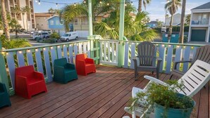 A wooden deck with colorful chairs and a potted plant.
