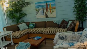 A cozy living room with a sectional sofa, a coffee table, and a painting of a beach scene.