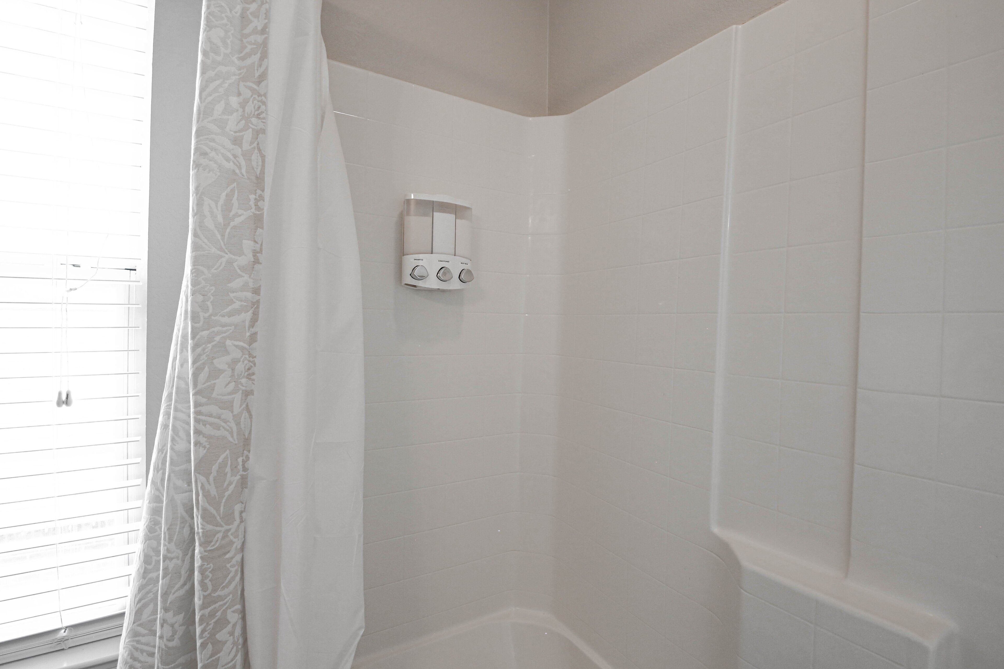 Ducha en esquina con azulejos blancos y panel de control.