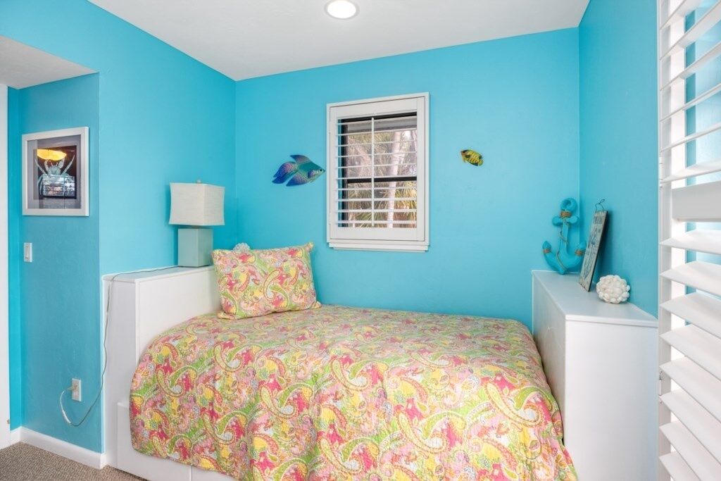 Un dormitorio con cama, ventana, lámpara y adornos en la pared.