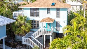 A two-story house with a blue exterior, a wooden staircase, and a small deck.