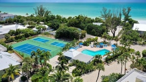 A resort with a tennis court, swimming pool, and beachfront views.