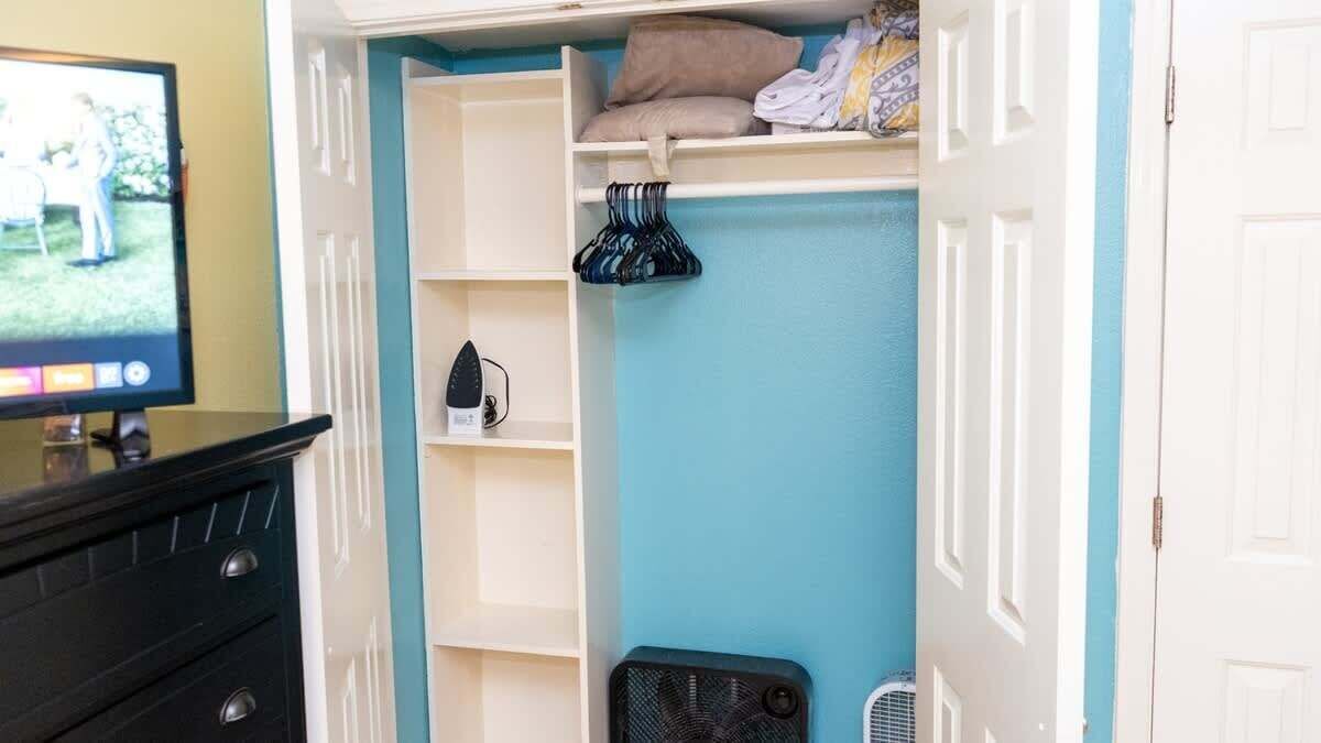 A room with a TV, a black dresser, a blue wall, and a white door.