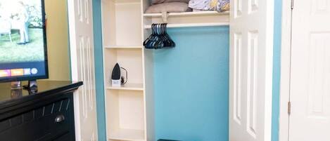 A room with a TV, a black dresser, a blue wall, and a white door.