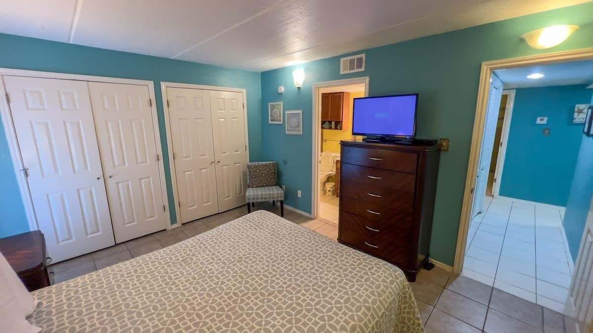 A bedroom with a bed, a dresser, a chair, and a television.