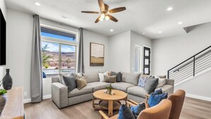 A modern living room with a sectional sofa, a round coffee table, and a ceiling fan.