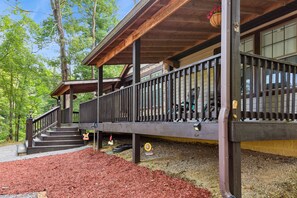 A wooden deck with a railing, steps leading up to a covered area, and a hanging flower basket.