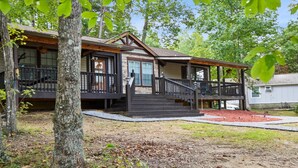 Une cabane à deux étages avec un porche, un escalier et une petite terrasse.