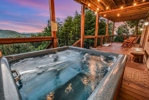 A hot tub on a wooden deck with a view of the surrounding landscape.