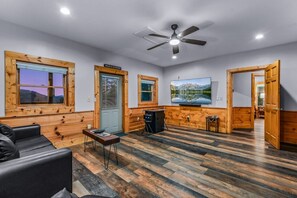 A spacious room with a ceiling fan, a large window with a view, and a wooden wall.