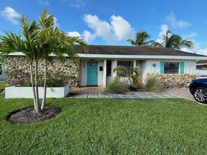 A single-story house with a stone facade, a teal door, and a small front porch. - Luxury Pool Dog Friendly Central To Naples And Marco Island By Sky Run Naples 3 Bedroom Home (Naples)