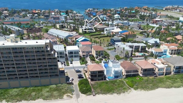Ett flygbildsbild av ett område vid stranden med ett hotell, parasoller och en fri utsikt över havet.