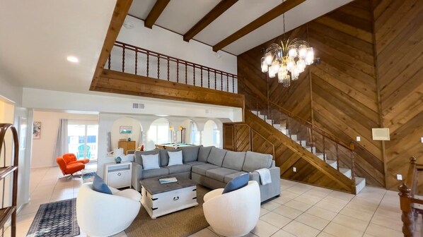 A spacious living area with a large sectional sofa, a coffee table, and a staircase with wooden railings.