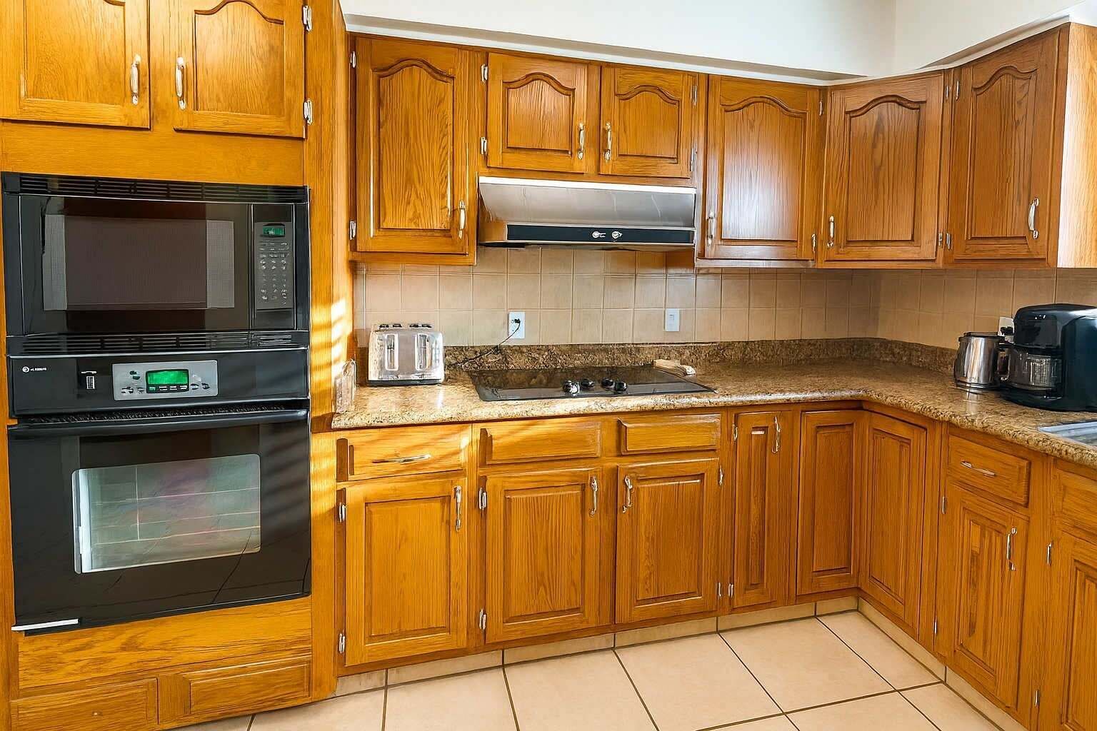 Una cocina con gabinetes de madera, microondas, tostadora y cafetera.