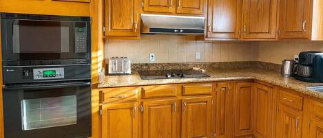 Una cocina con gabinetes de madera, microondas, tostadora y cafetera.