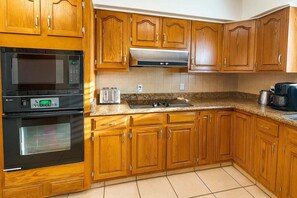 A kitchen with wooden cabinets, a microwave, a toaster, and a coffee maker. - Fun Retro Island Vibe Sleeps 17 Beach 1 Block 4 Bedroom Home (South Padre Island)