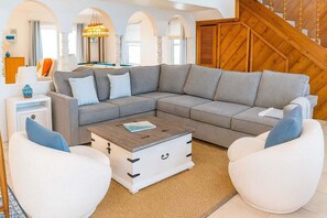 A modern living room with a grey sectional sofa, white armchairs, and a wooden coffee table. - Fun Retro Island Vibe Sleeps 17 Beach 1 Block 4 Bedroom Home (South Padre Island)