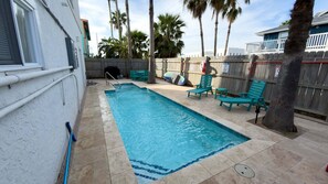 A rectangular swimming pool with a tiled edge, surrounded by a wooden fence, and equipped with a ladder. - Fun Retro Island Vibe Sleeps 17 Beach 1 Block 4 Bedroom Home (South Padre Island)