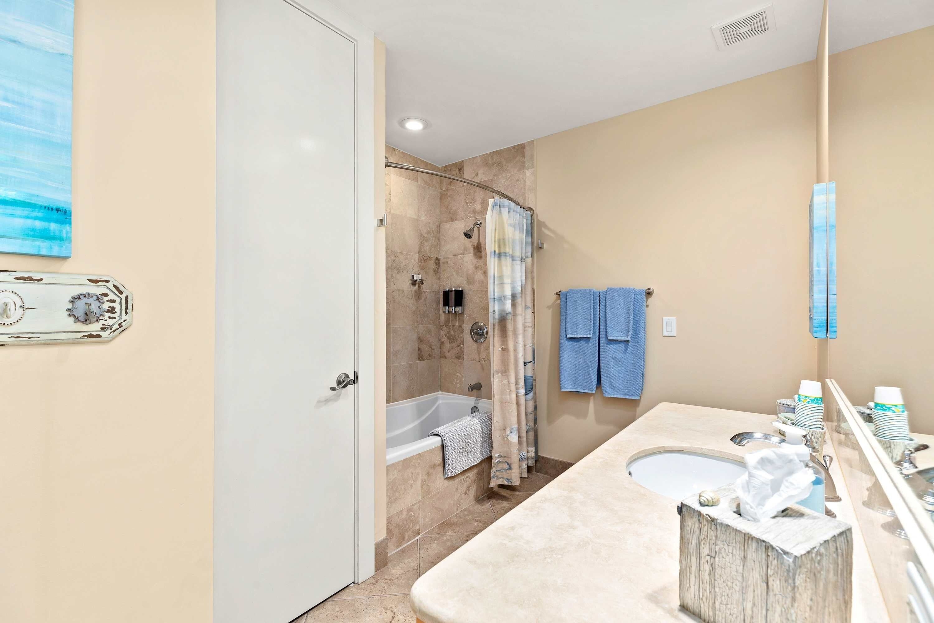 A bathroom with a bathtub, shower, and sink. There are towels hanging on the wall and a mirror above the sink.