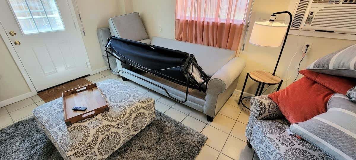Un espacio habitable pequeño con un sofá, una mesita, una lámpara y un tapete estampado.