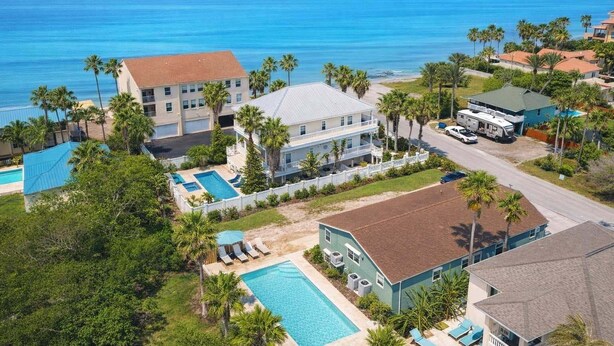 A coastal property with multiple buildings, a swimming pool, and a view of the ocean.