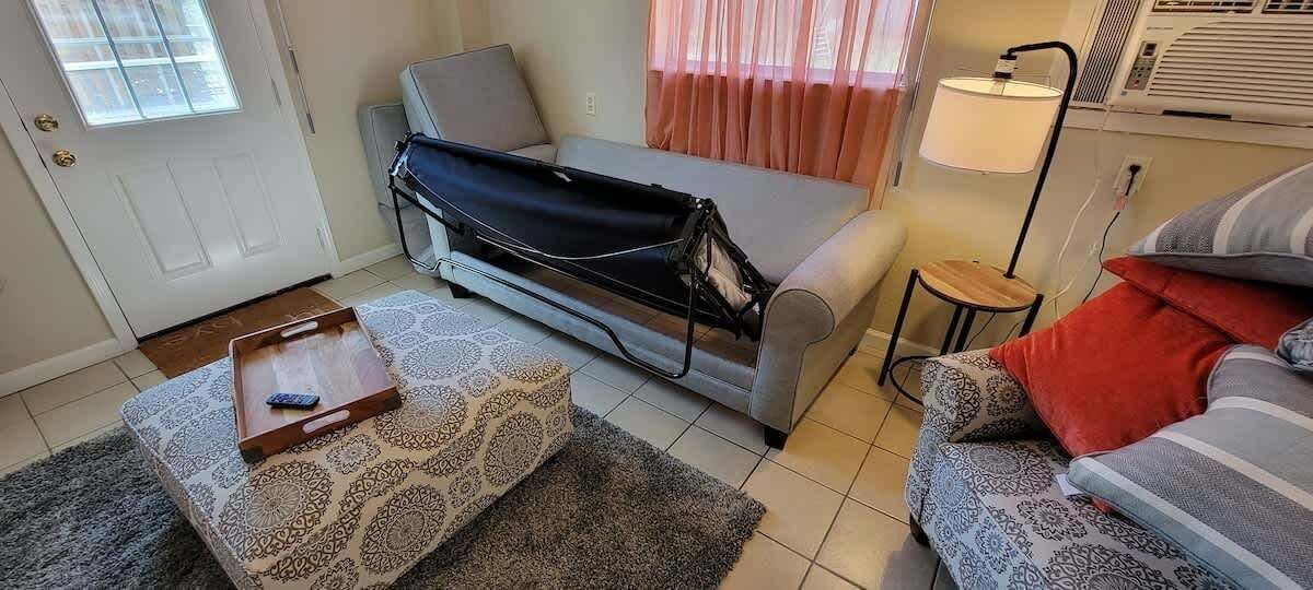 A compact living space with a sofa, a small table with a tray, a patterned rug, and a lamp.