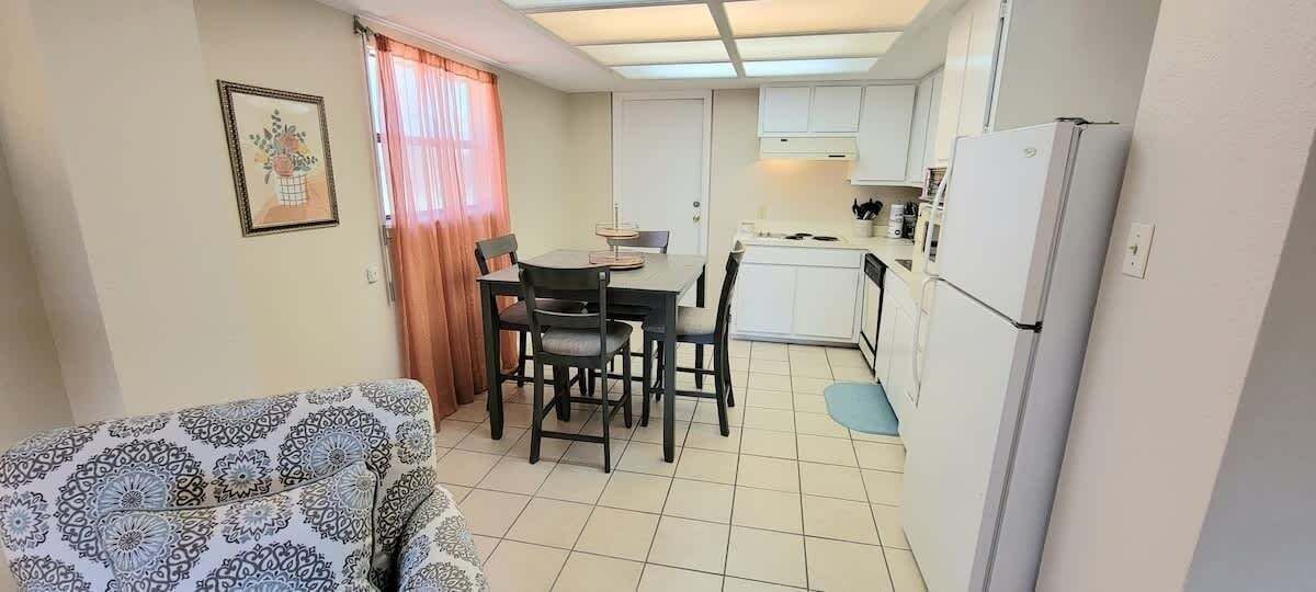 Eine kleine Küche mit Esstisch, Stühlen und einem Kühlschrank.