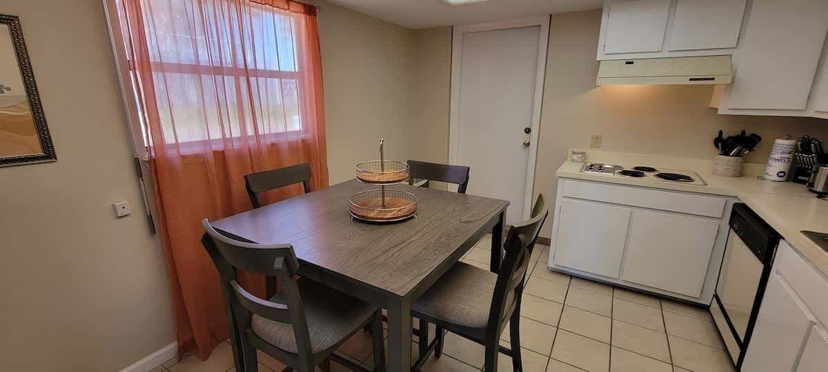 A compact kitchen with a dining table, chairs, a stove, and a sink.