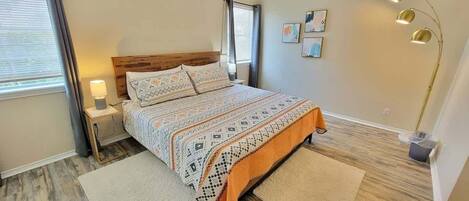 A bedroom with a bed, nightstands, a lamp, and artwork on the wall.