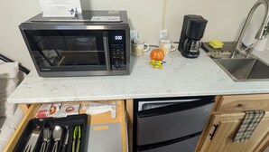 A compact kitchen with a microwave, coffee maker, and a sink.