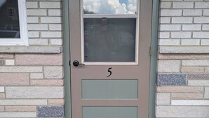 A house number 5 on a beige door with a window above it.
