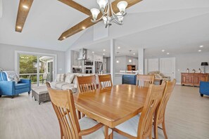 Un vaste espace de vie comprenant une table à manger, des chaises et une cuisine en arrière-plan.