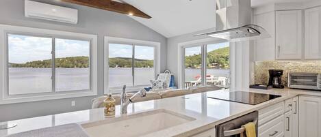 A kitchen with a large island, white cabinetry, and a view of a lake.