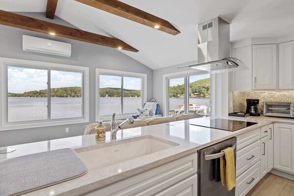 A kitchen with a large island, white cabinetry, and a view of a lake.
