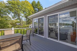 Une terrasse couverte, aménagée avec du mobilier d’extérieur, de grandes portes-fenêtres coulissantes et une vue sur un paysage verdoyant.