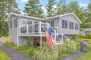 Une maison à deux étages avec un balcon, un drapeau et un barbecue.