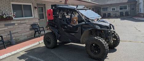 A black ATV parked in front of a building with a brick facade, a window, and a door.