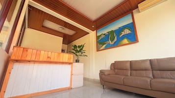 Un área de recepción con un mostrador de madera, un sofá de cuero marrón y un cuadro de un paisaje costero en la pared.