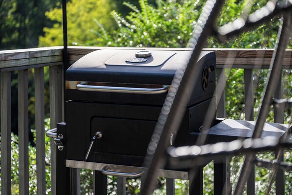 Un barbecue sur une terrasse en bois, avec une rambarde en métal.