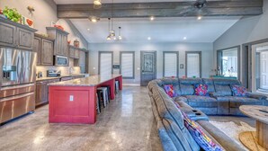 A spacious living area with a large sofa, a kitchen with modern appliances, and a ceiling fan.