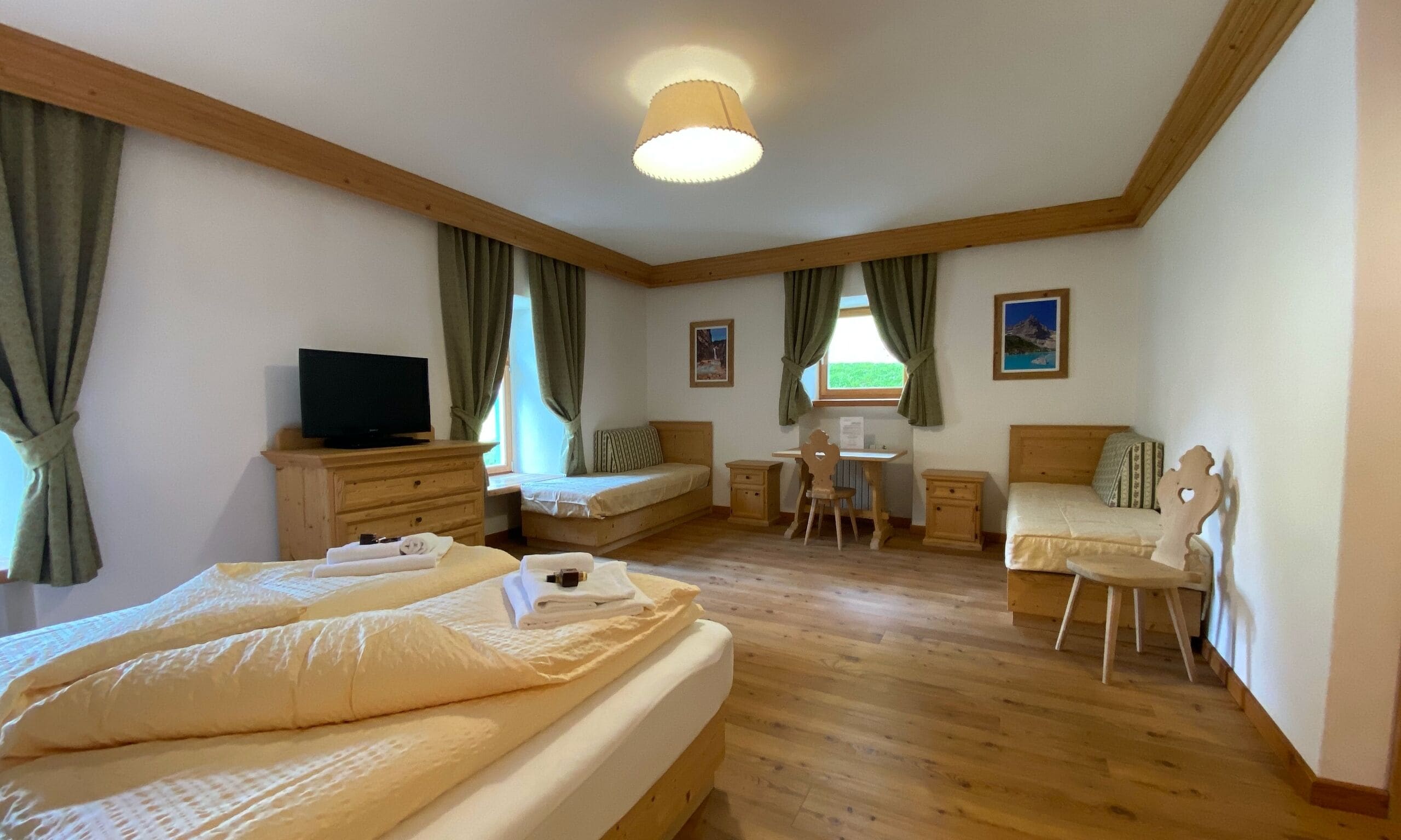 A hotel room with two beds, a desk, a chair, a television, and a window with curtains.