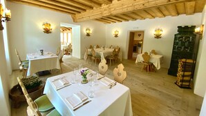 Un espace repas avec des nappes blanches, des chaises en bois et des luminaires fixés au mur.