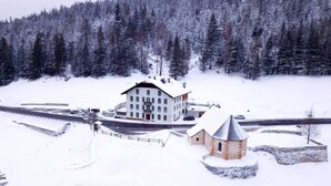 Un grand bâtiment doté de nombreuses fenêtres et d’un toit recouvert de neige, entouré d’une forêt.