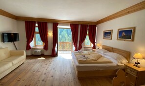 A bedroom with a wooden floor, a bed, a TV, and a balcony with red curtains. - Rifugio Ospitale (Cortina d'Ampezzo)