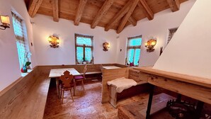 Une pièce chaleureuse avec des poutres apparentes, une table en bois, des bancs et une cheminée.