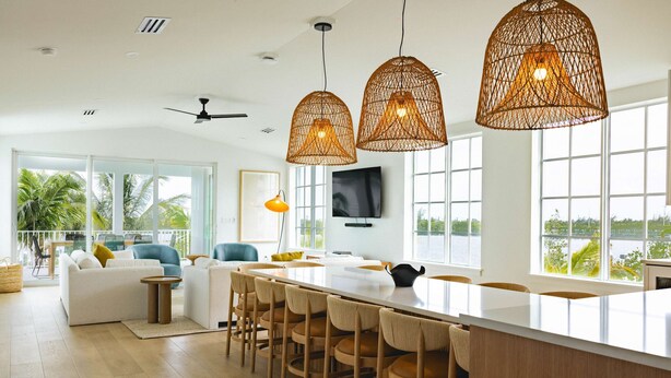 A modern kitchen with a large island, bar stools, and pendant lighting. - The Joyrise House at Solaire Lunara Bay (Key West)