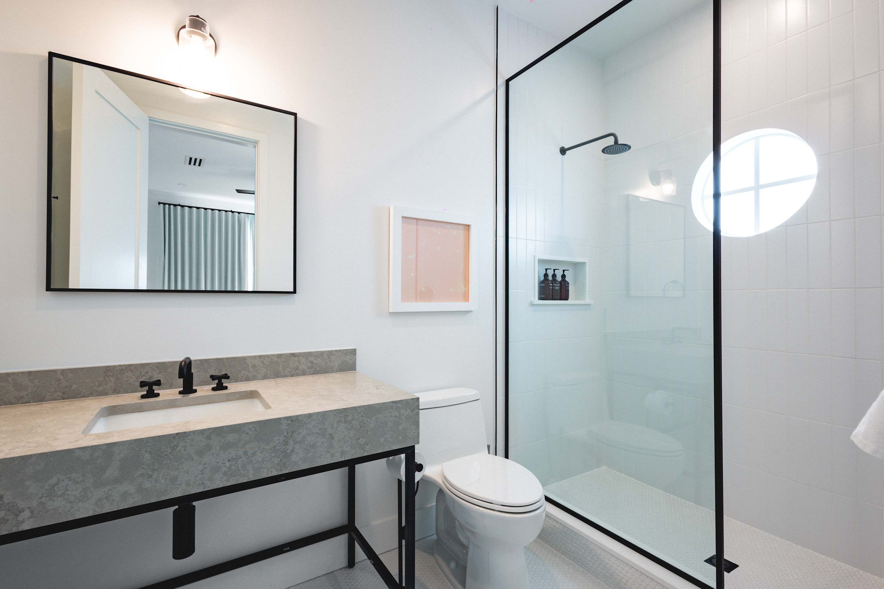 A modern bathroom with a glass-enclosed shower, a sink with a marble countertop, and a toilet.